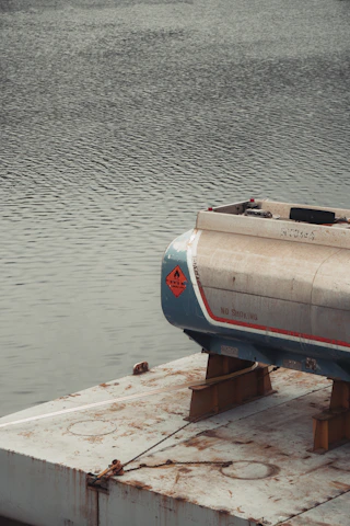 A fuel tank rests on a platform over water.