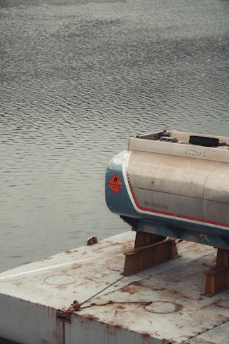 A fuel tank rests on a platform over water.