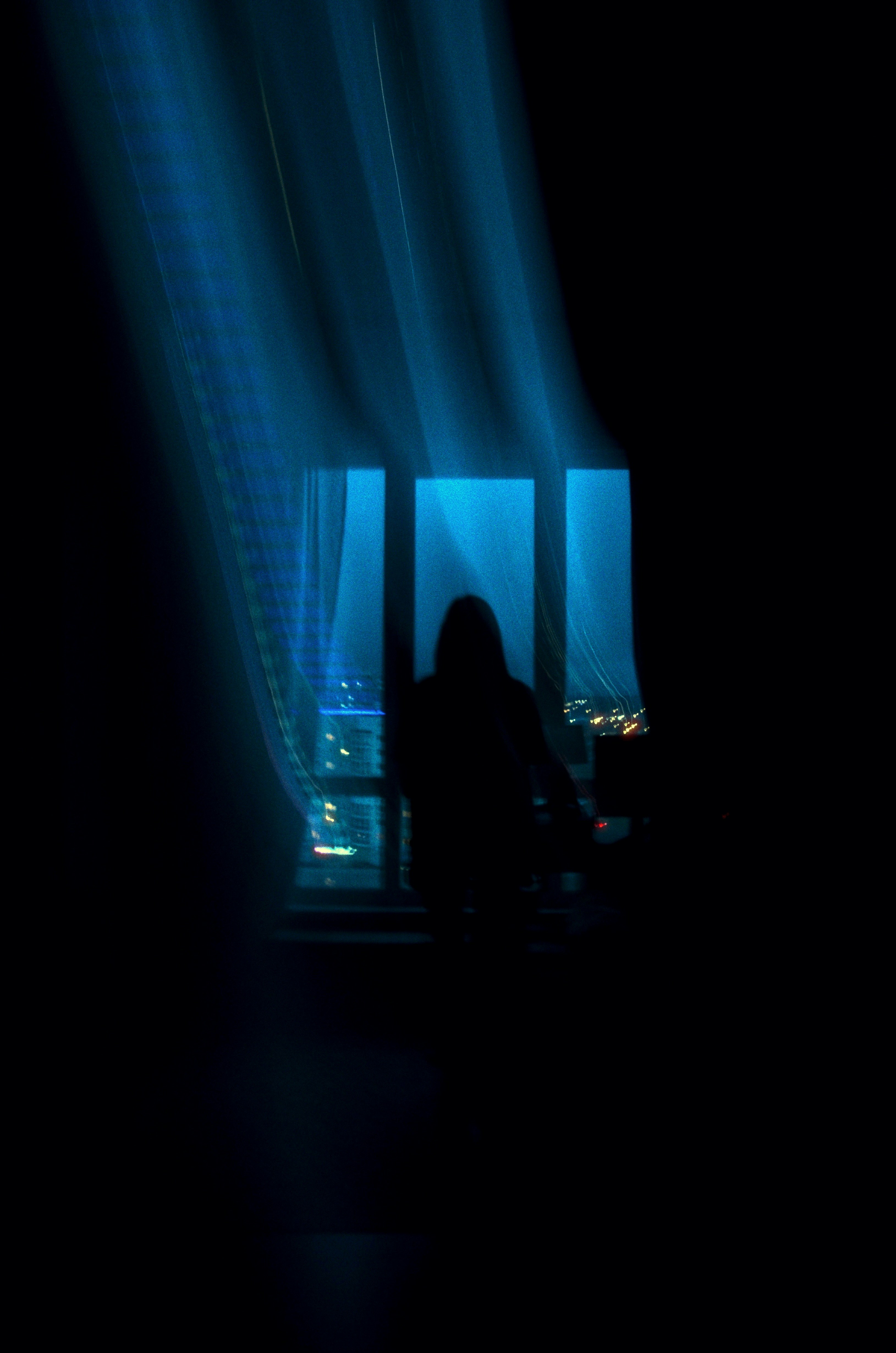 Silhouette of a person by a window at night.