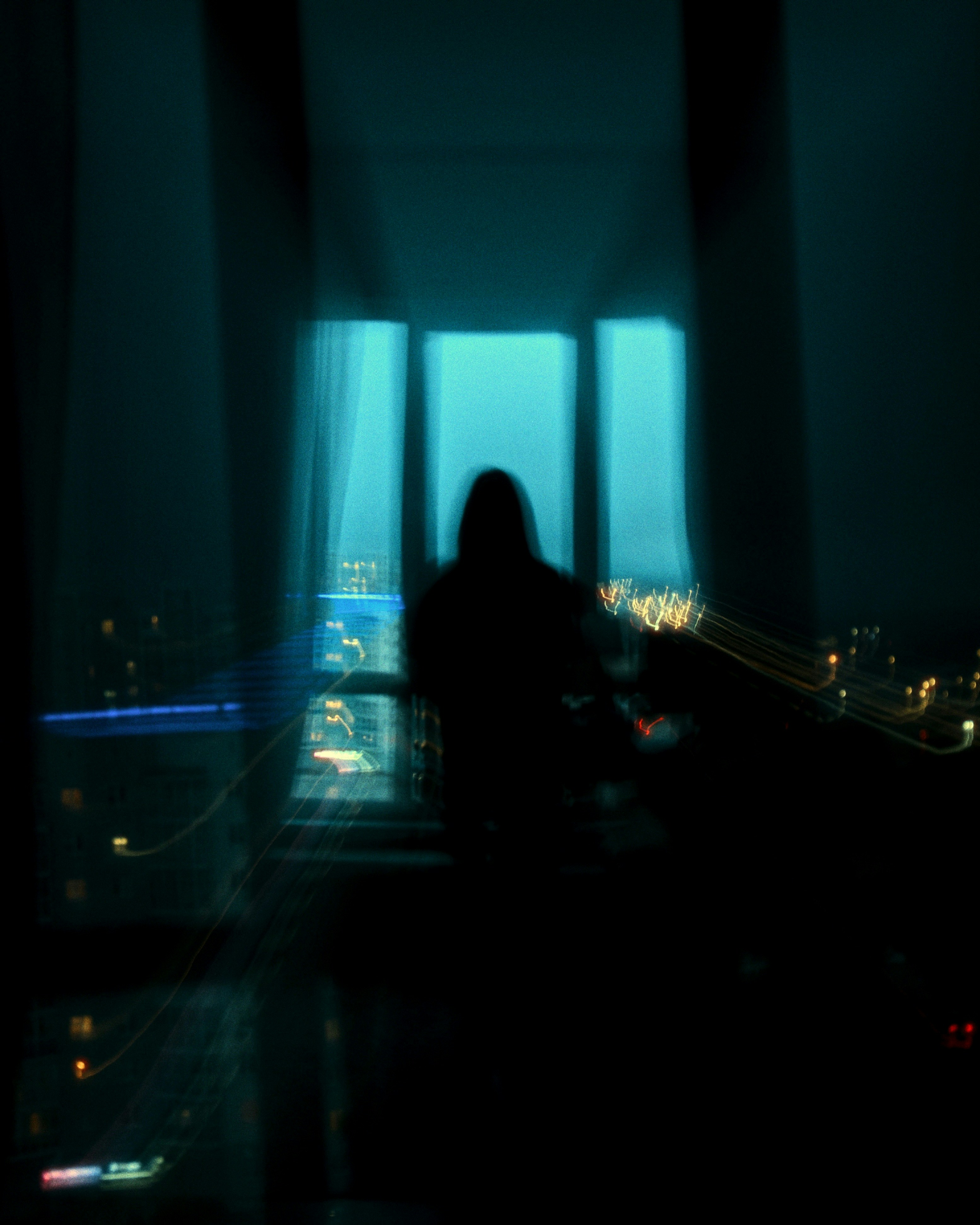 Silhouette of a person looking out a window at night.