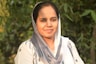A woman wearing a headscarf smiles at the camera.