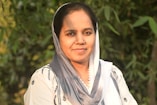 A woman wearing a headscarf smiles at the camera.