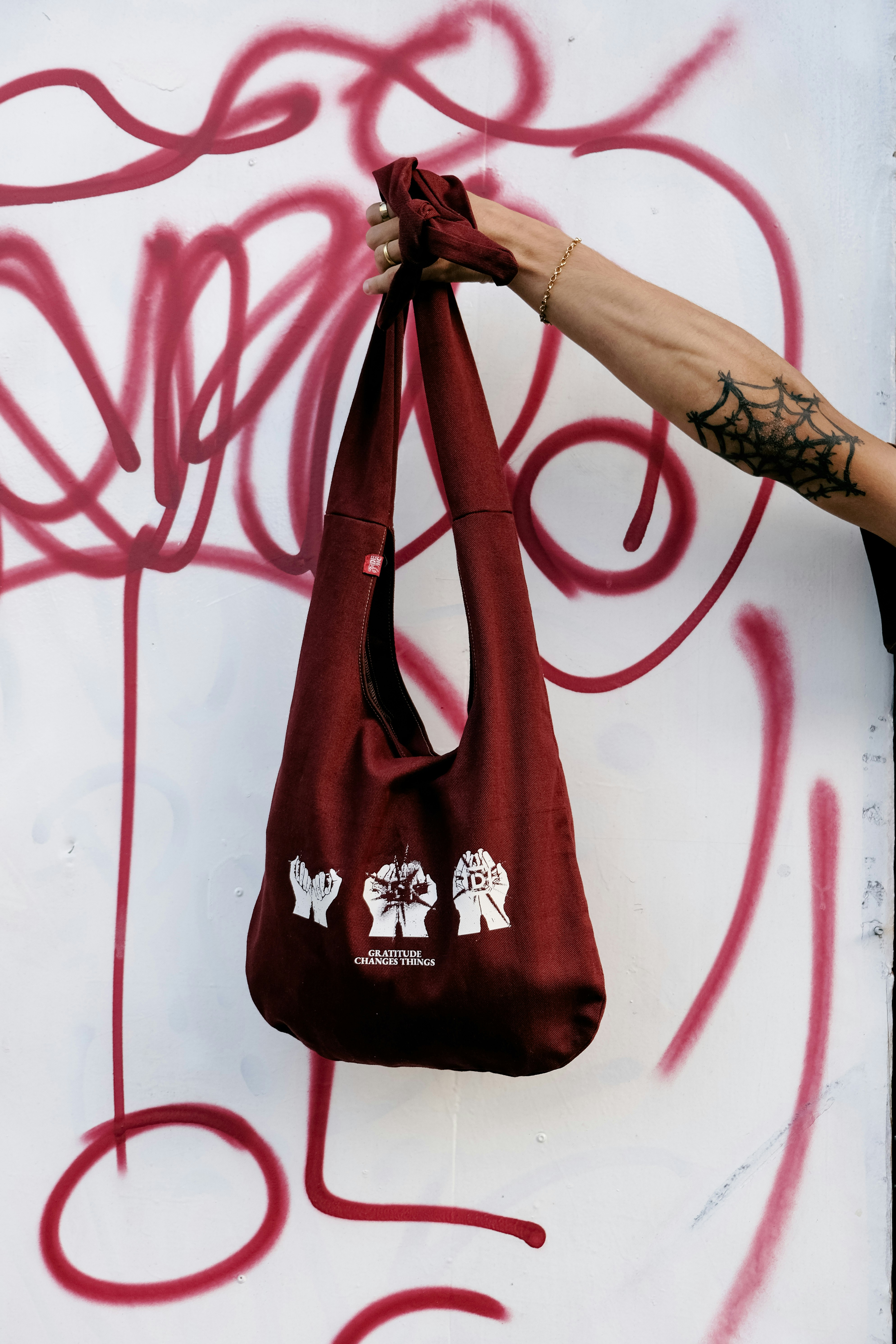 Une personne tient un sac marron contre les graffitis.