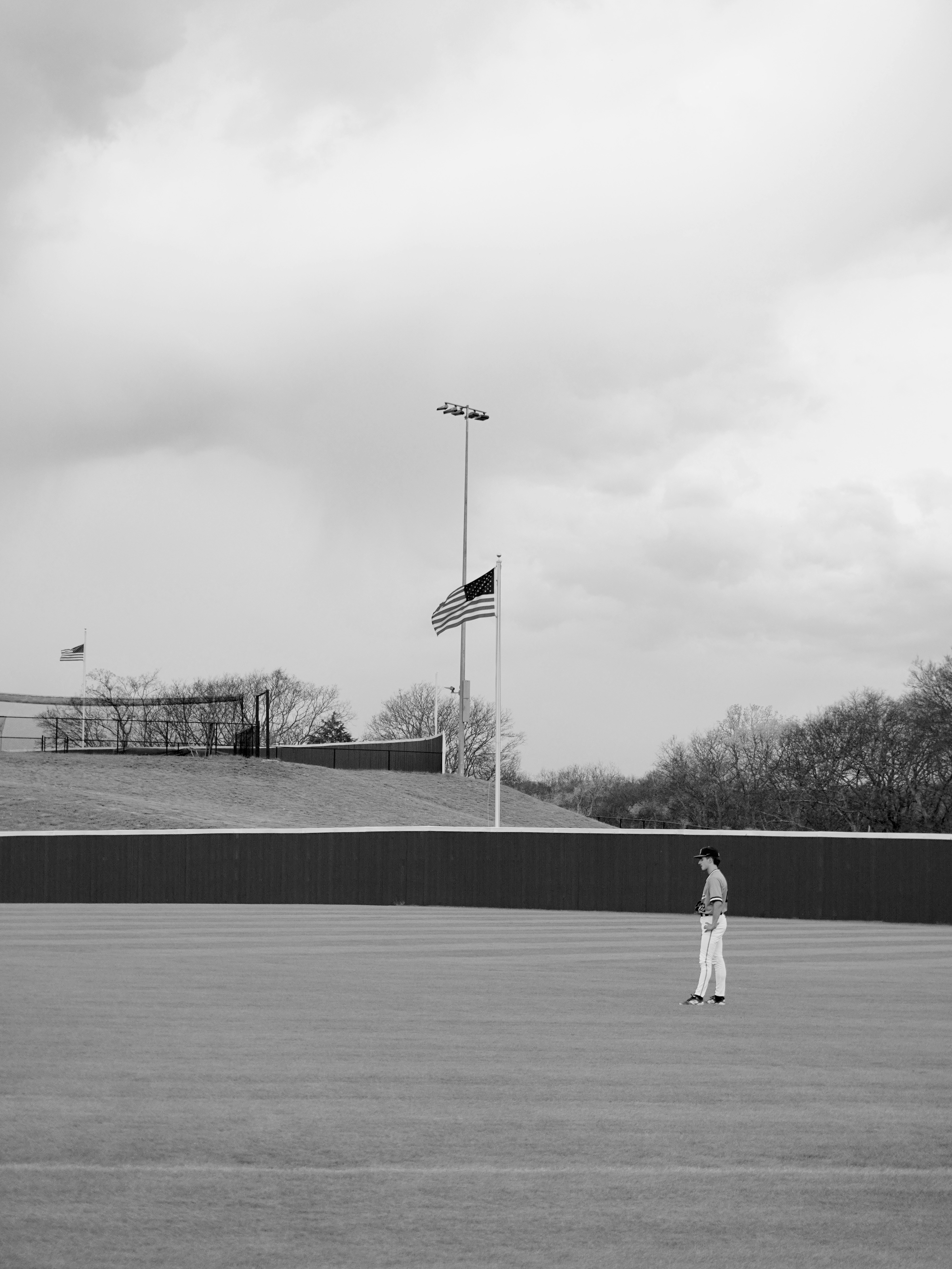 A lone figure stands on a baseball field.
