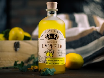 Limoncello bottle with lemons and greens on display.