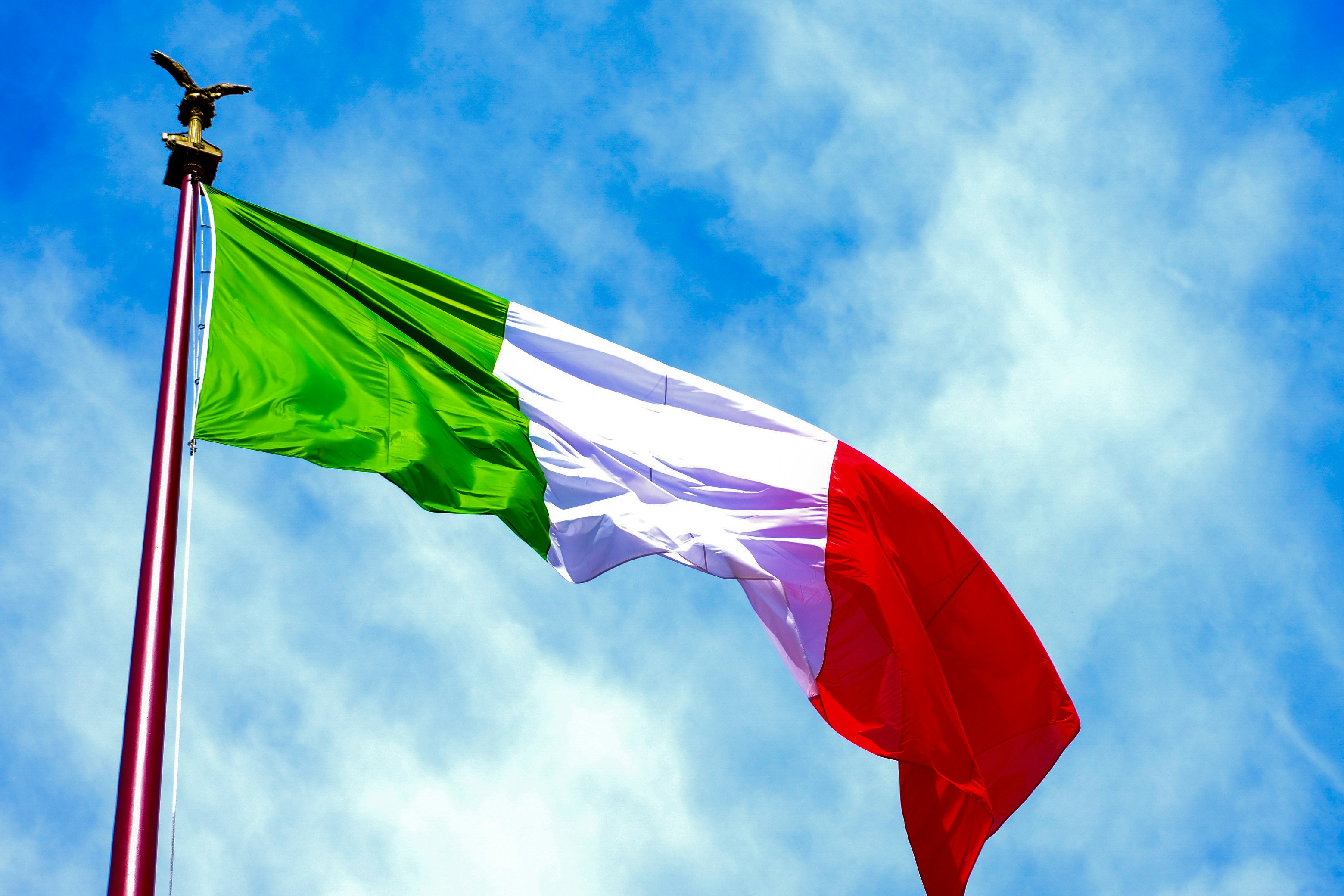 The italian flag waves in the blue sky.