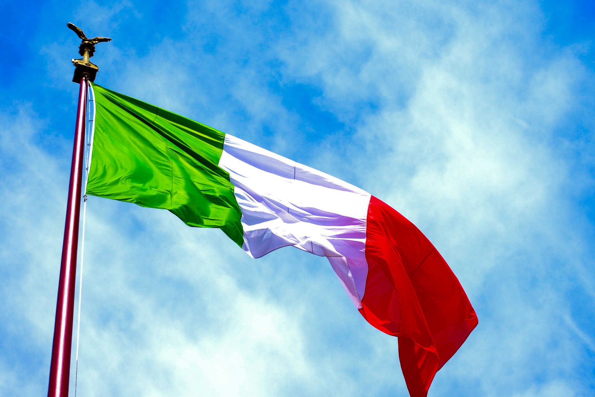The italian flag waves in the blue sky.