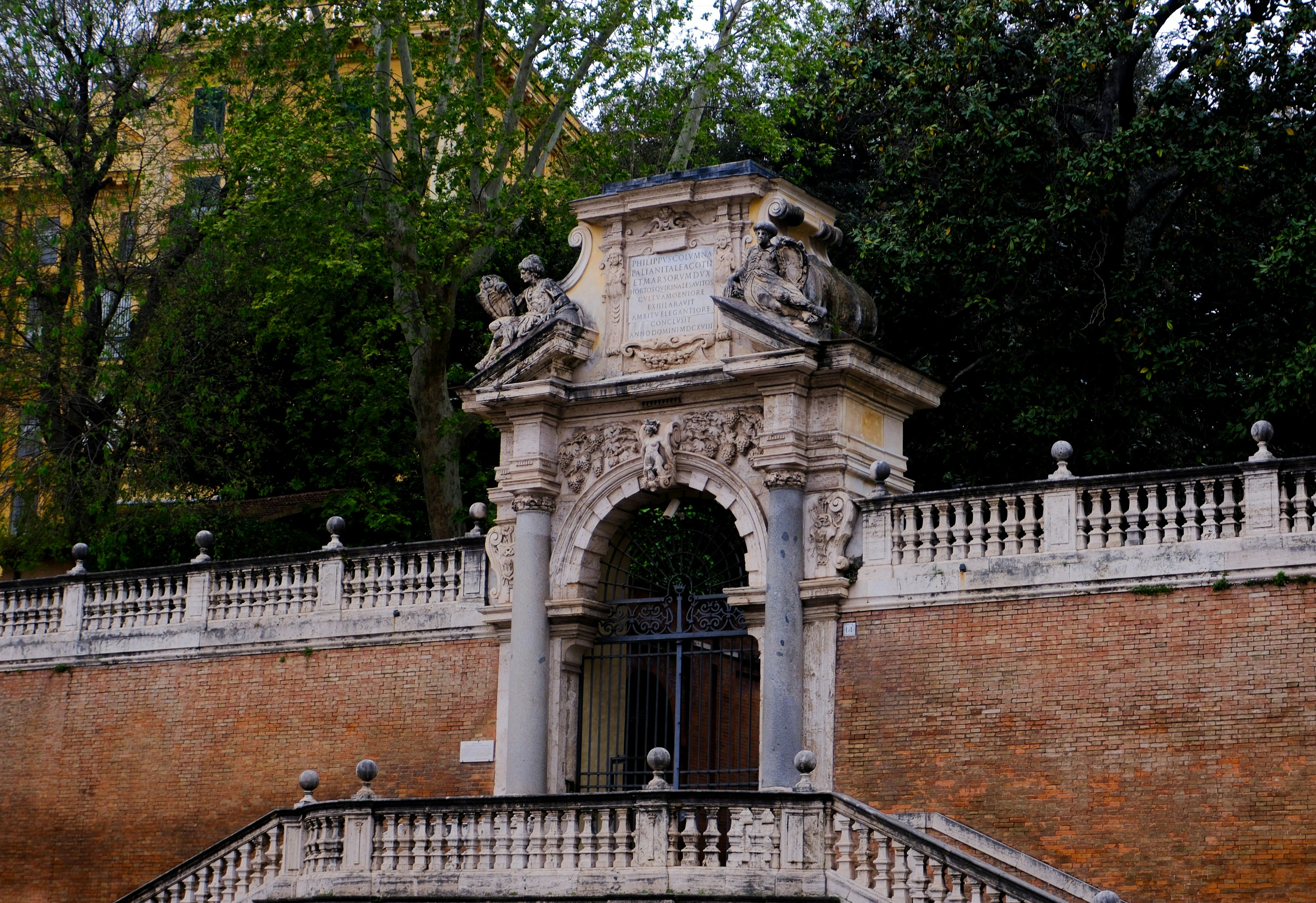An ornate archway stands atop a brick wall.
