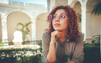 A woman with curly hair poses outdoors.