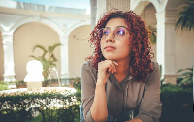 A woman with curly hair poses outdoors.