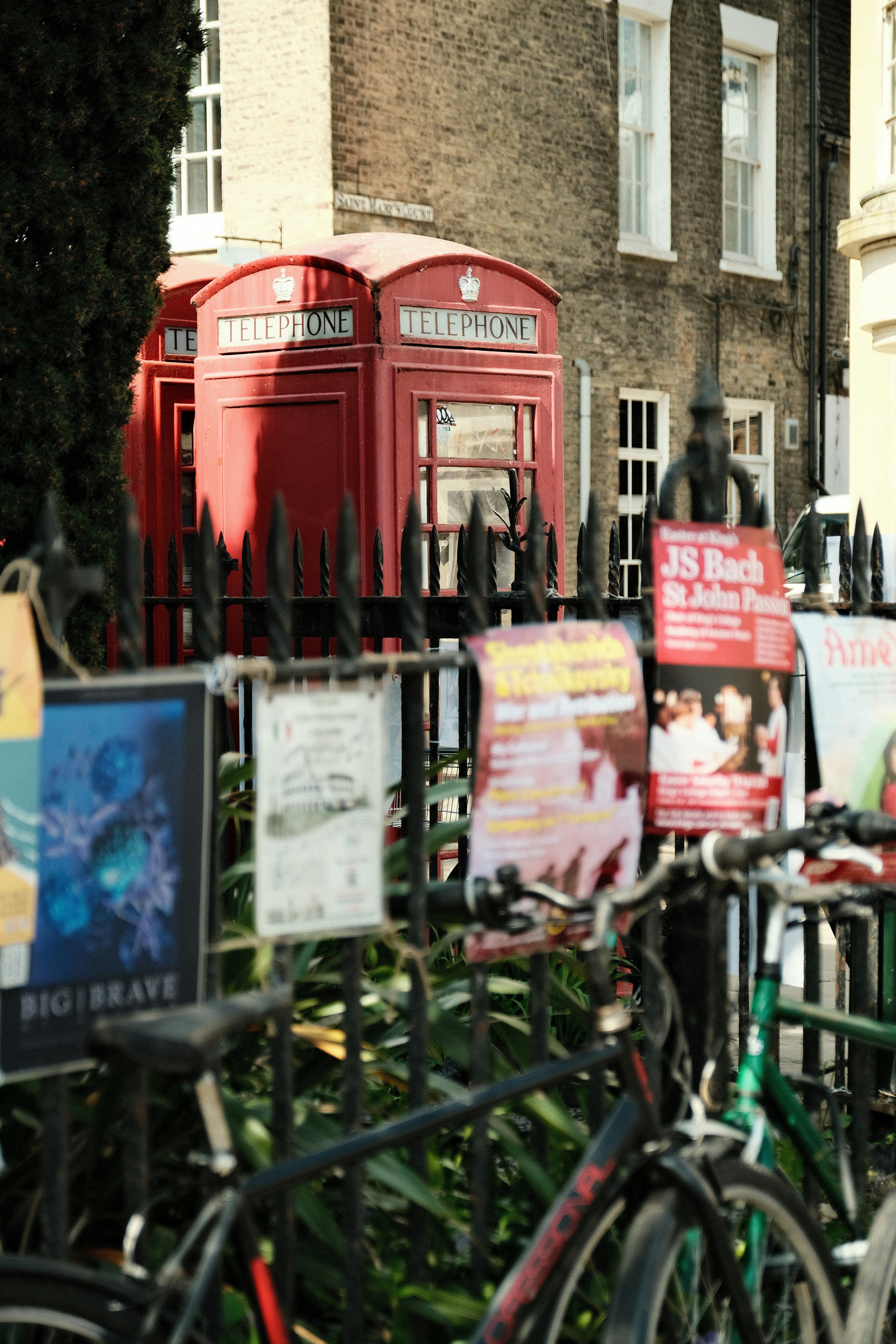 Red telephone boxes stand in a vibrant city scene.