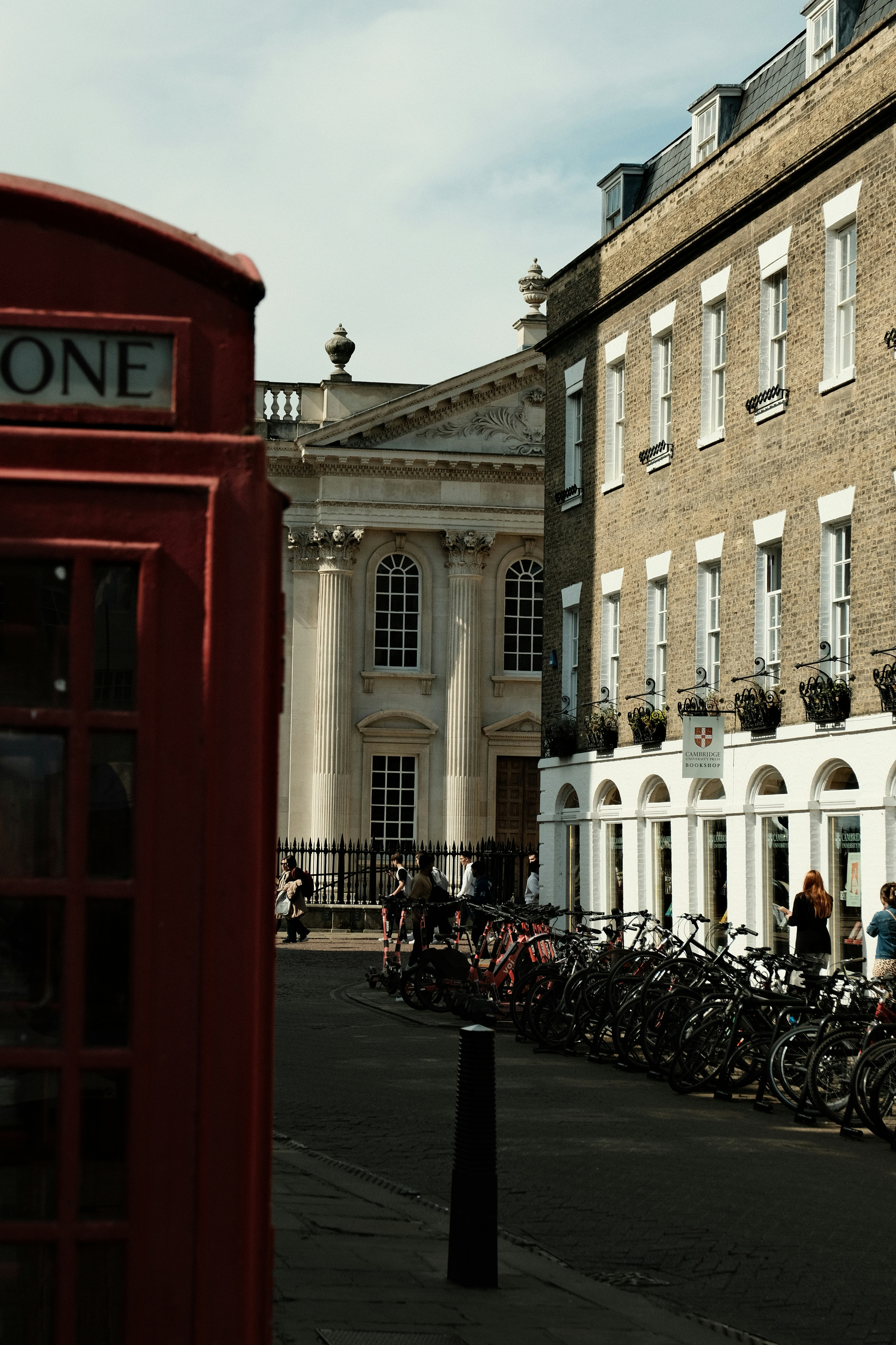 A red phone booth stands near historic buildings.