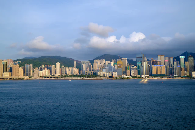The island skyline across the harbour from the Tsim Sha Tsui promenade, blue sky