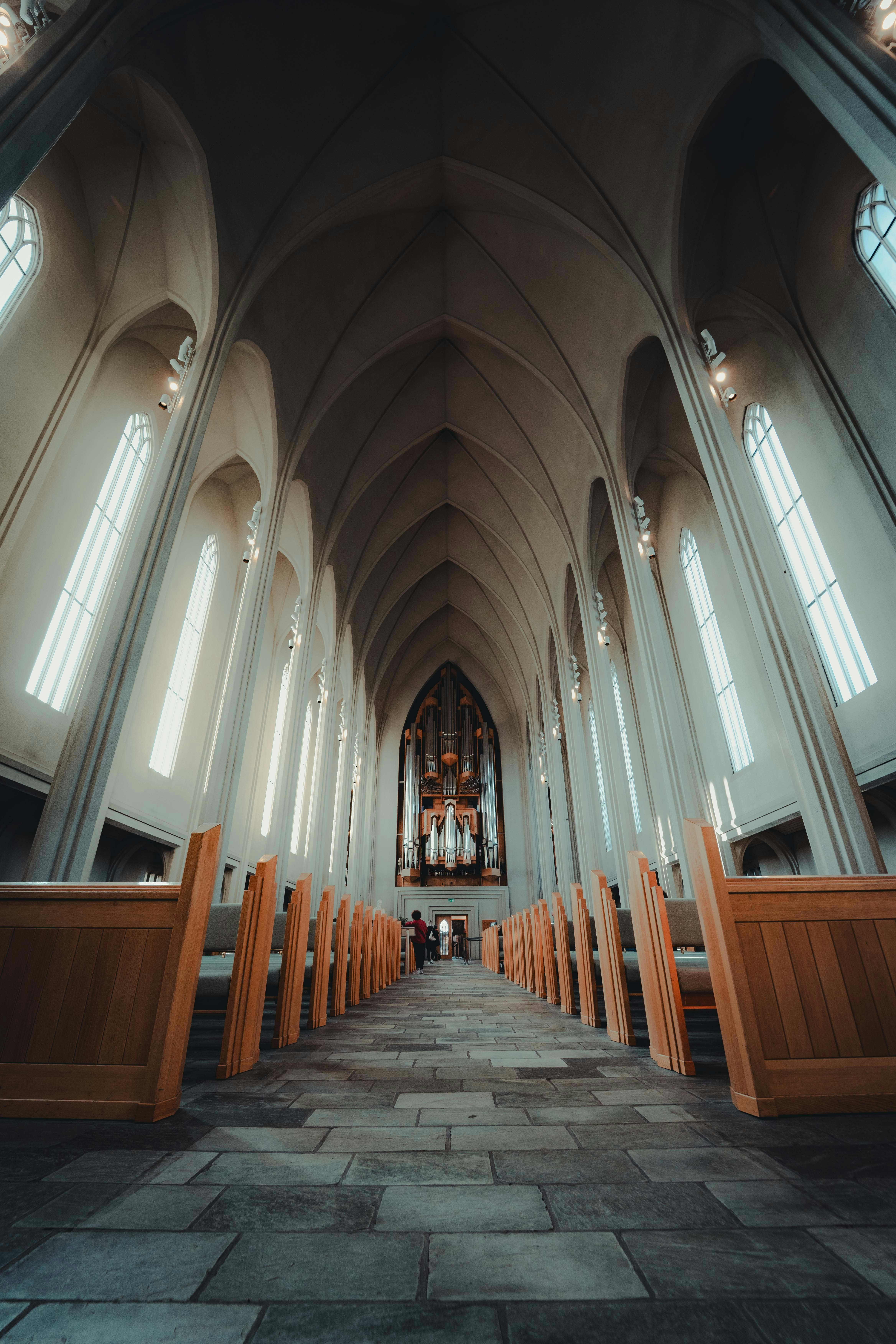 Dentro de uma catedral com bancos e janelas altas.