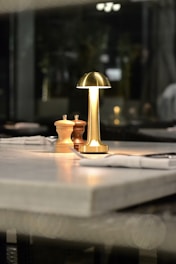 A lamp and salt shakers sit on a restaurant table.
