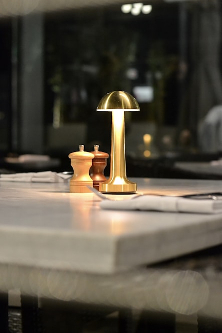 A lamp and salt shakers sit on a restaurant table.