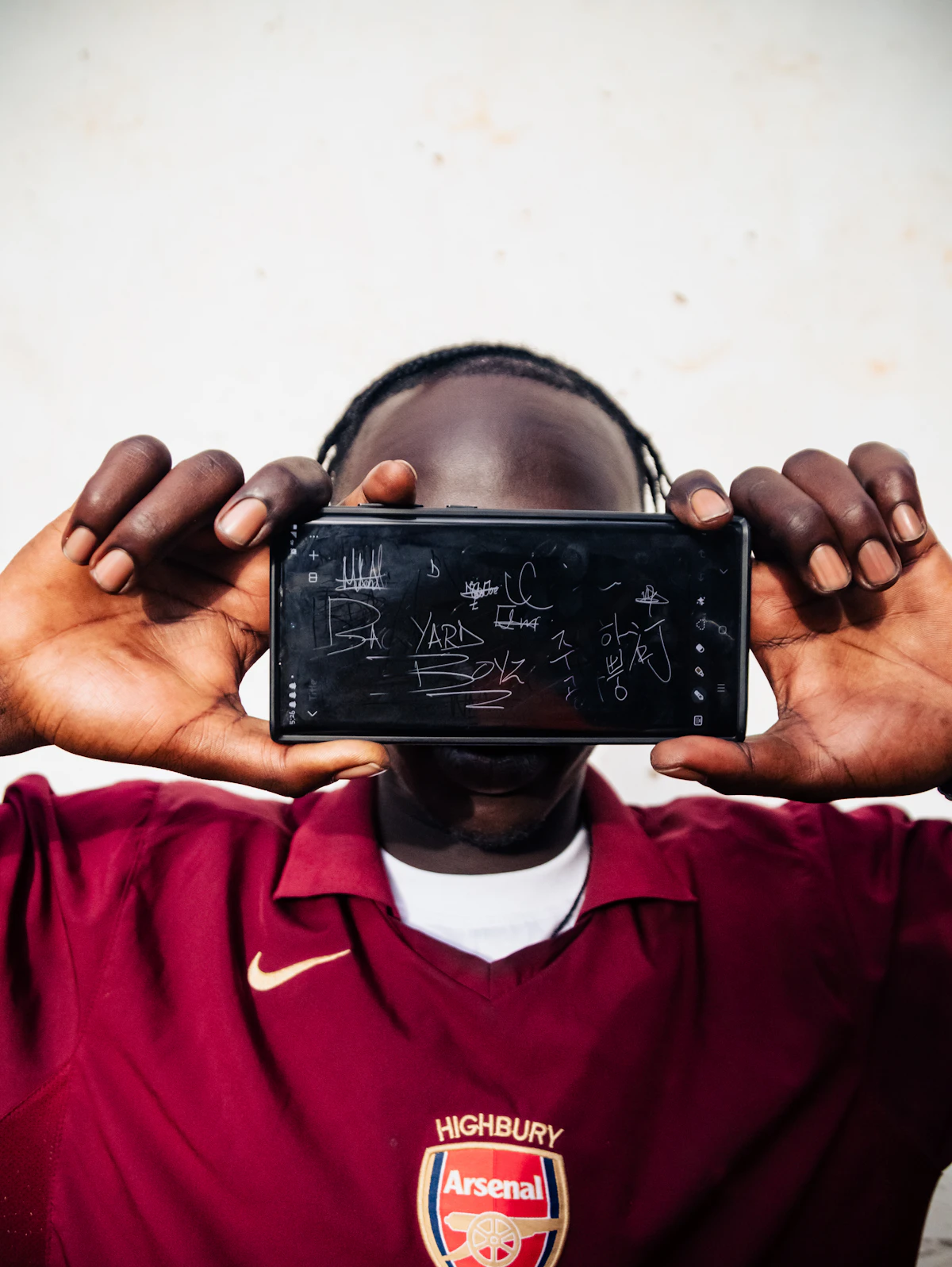 Person holds phone covering face with graffiti