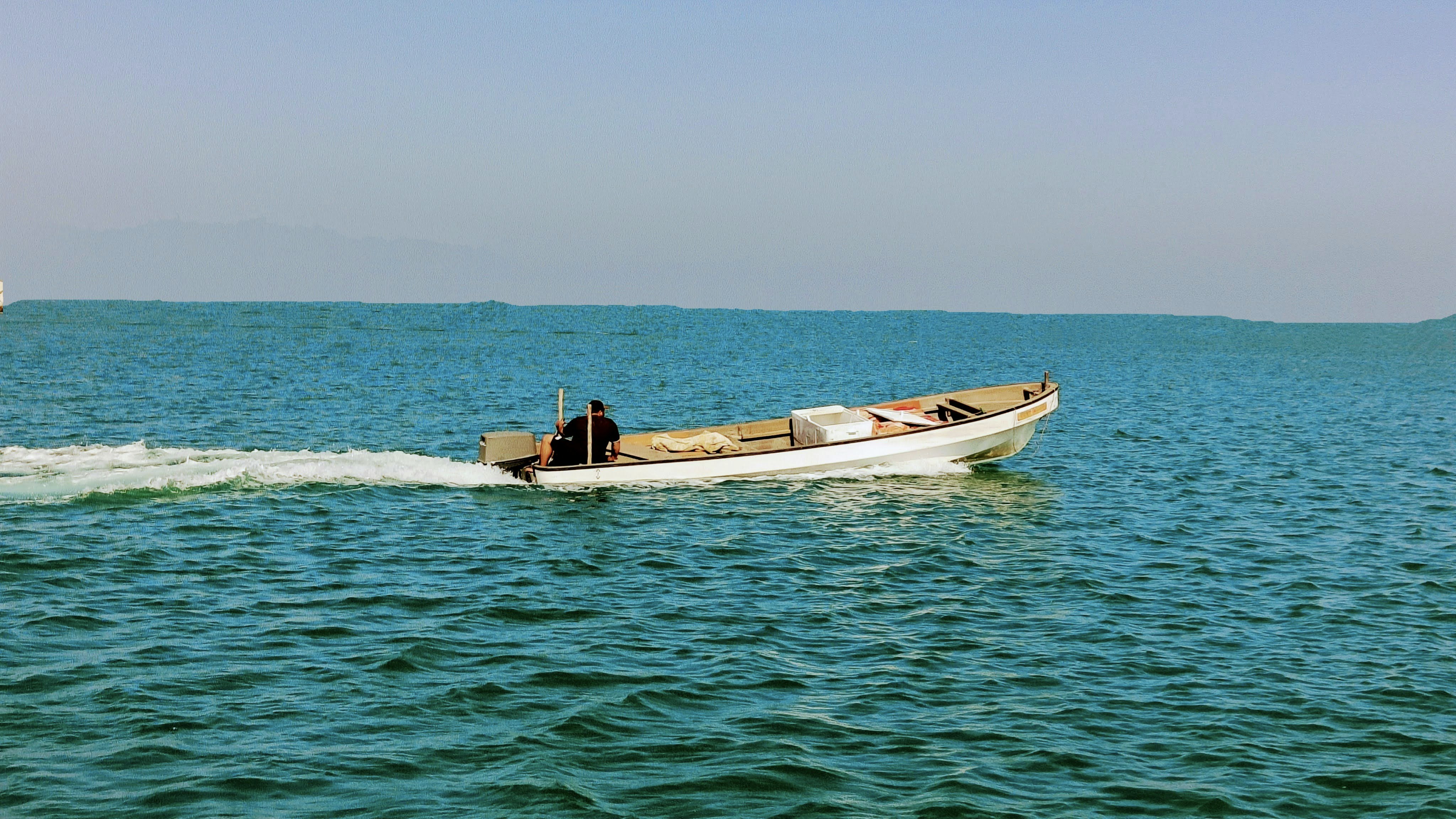 A small boat speeds across the blue ocean waters.