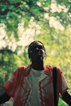 Young man looks up, framed by lush green foliage.