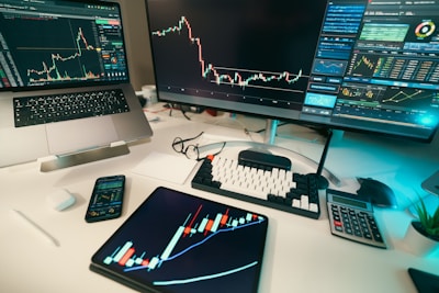 Stock charts are displayed on multiple screens.