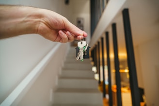 Here's a possible caption: keys being held in front of a staircase.