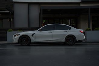 A white BMW sedan parked by a building.