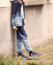A boy is leaning against a wall.