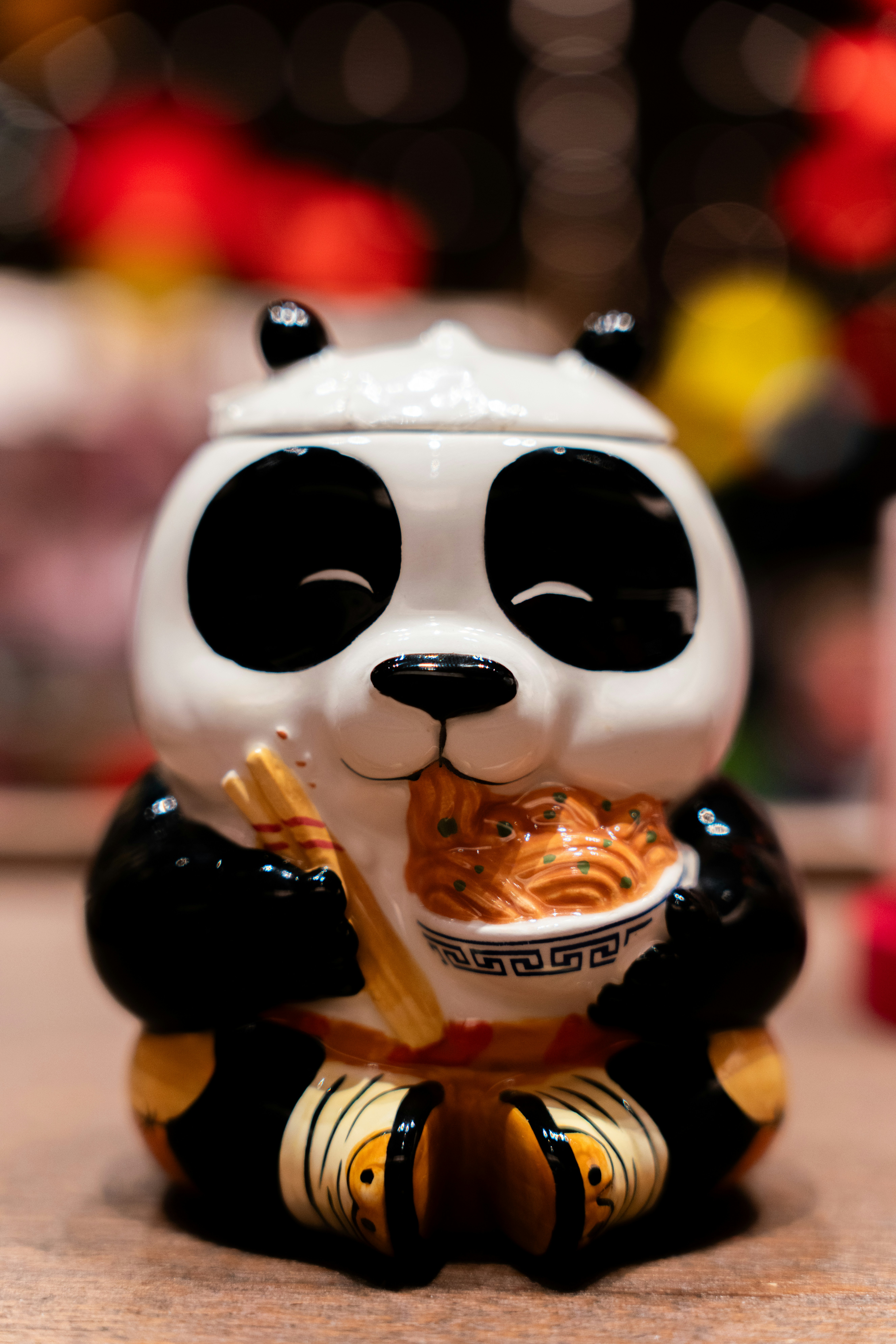A ceramic panda cookie jar is eating noodles.
