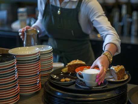 A waitress serves cake and coffee.
