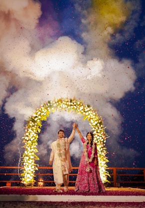 Couple celebrates under a floral arch with confetti.