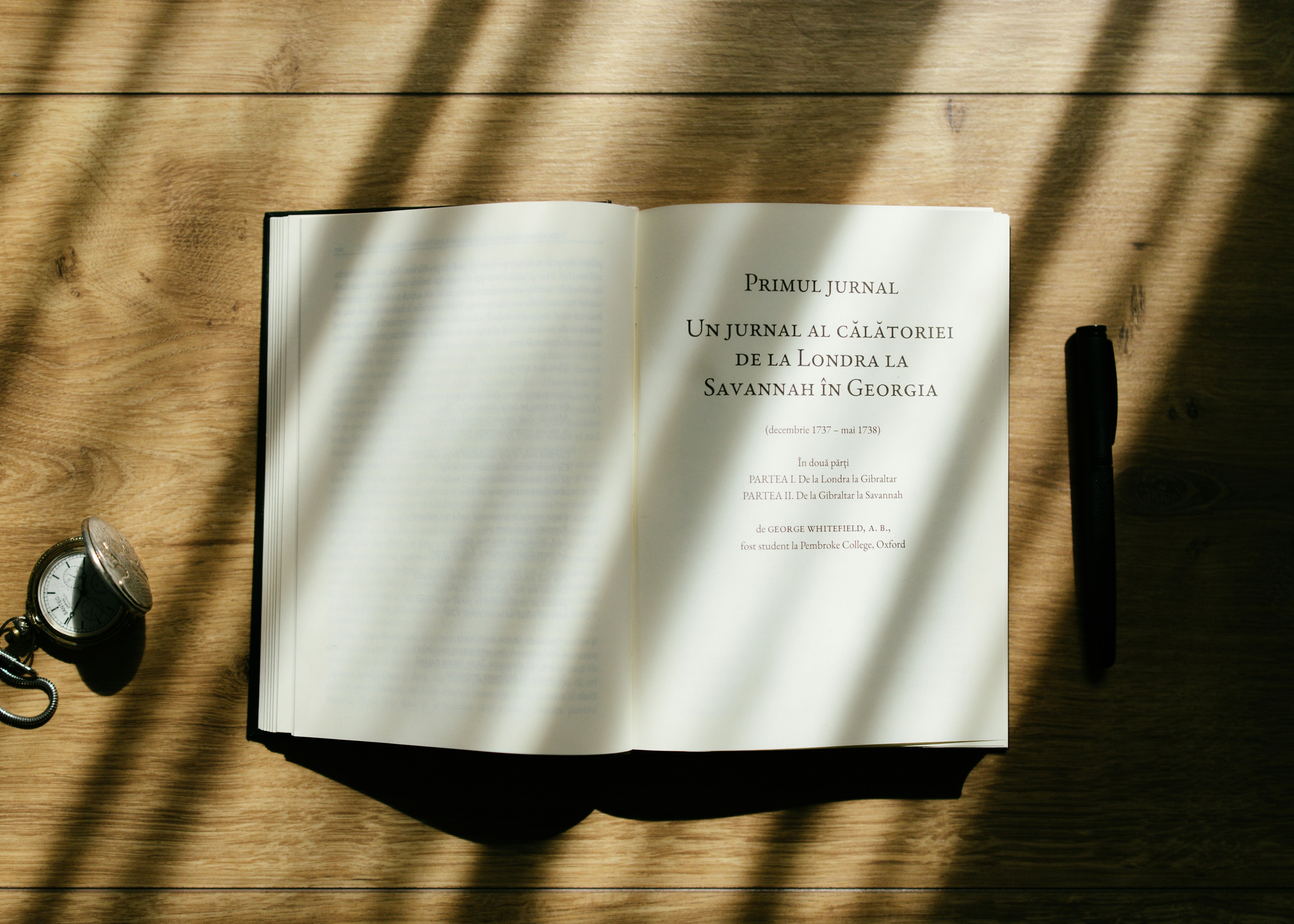 An open book lies on a wooden table.