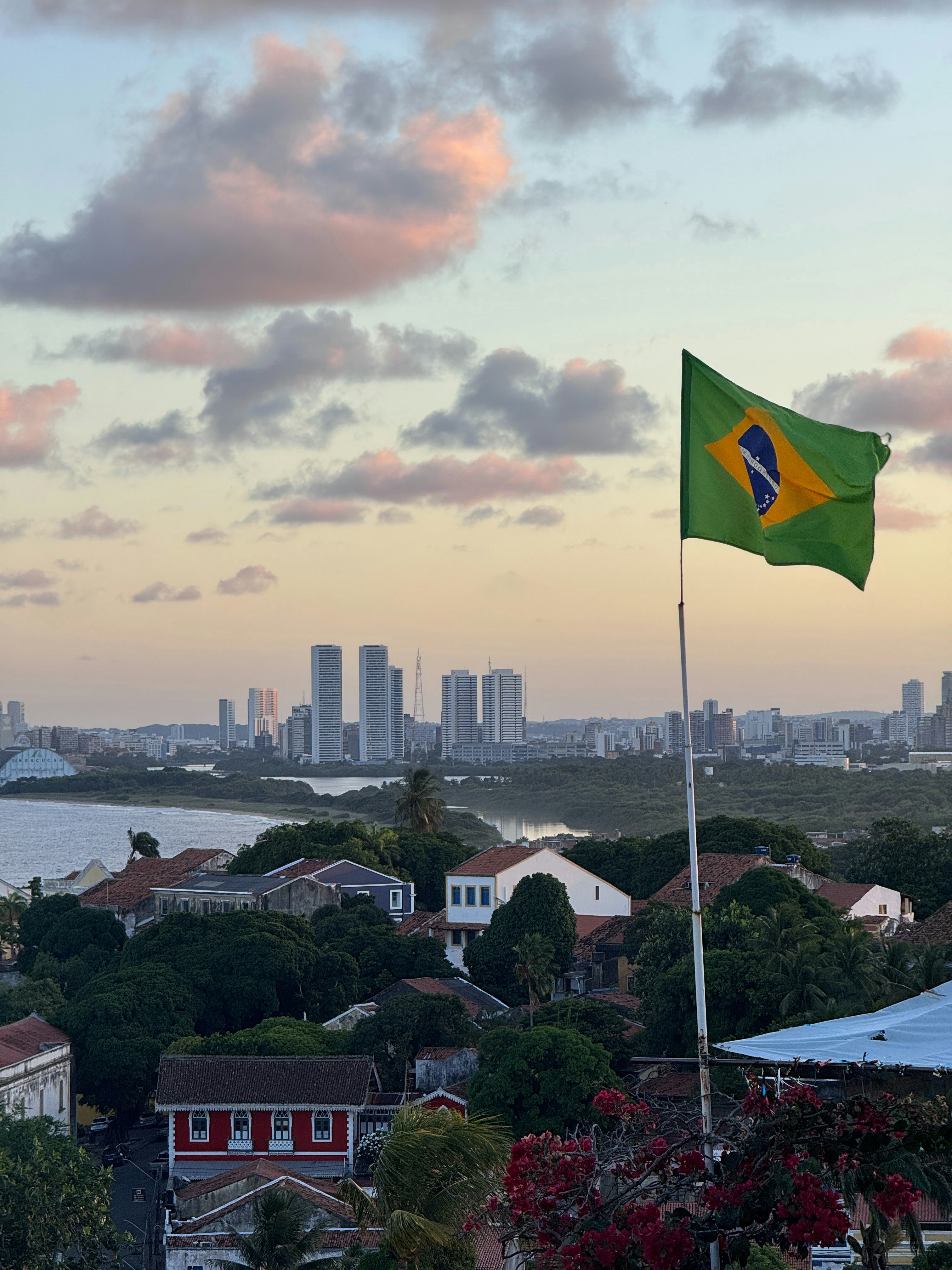 Brazilian flag waving over a coastal city.