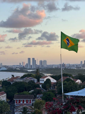 Brazilian flag waving over a coastal city.