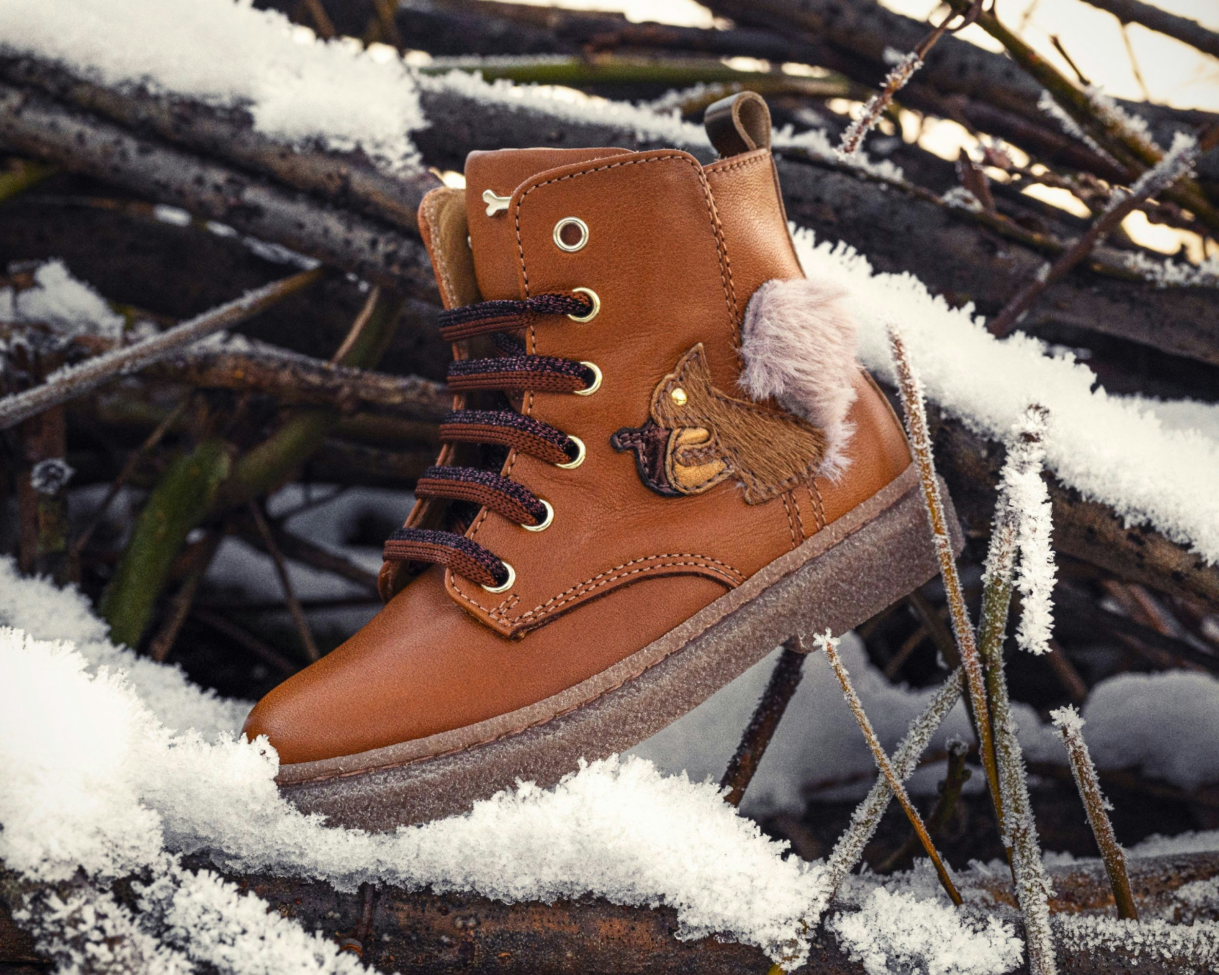 A brown boot is resting in the snow.