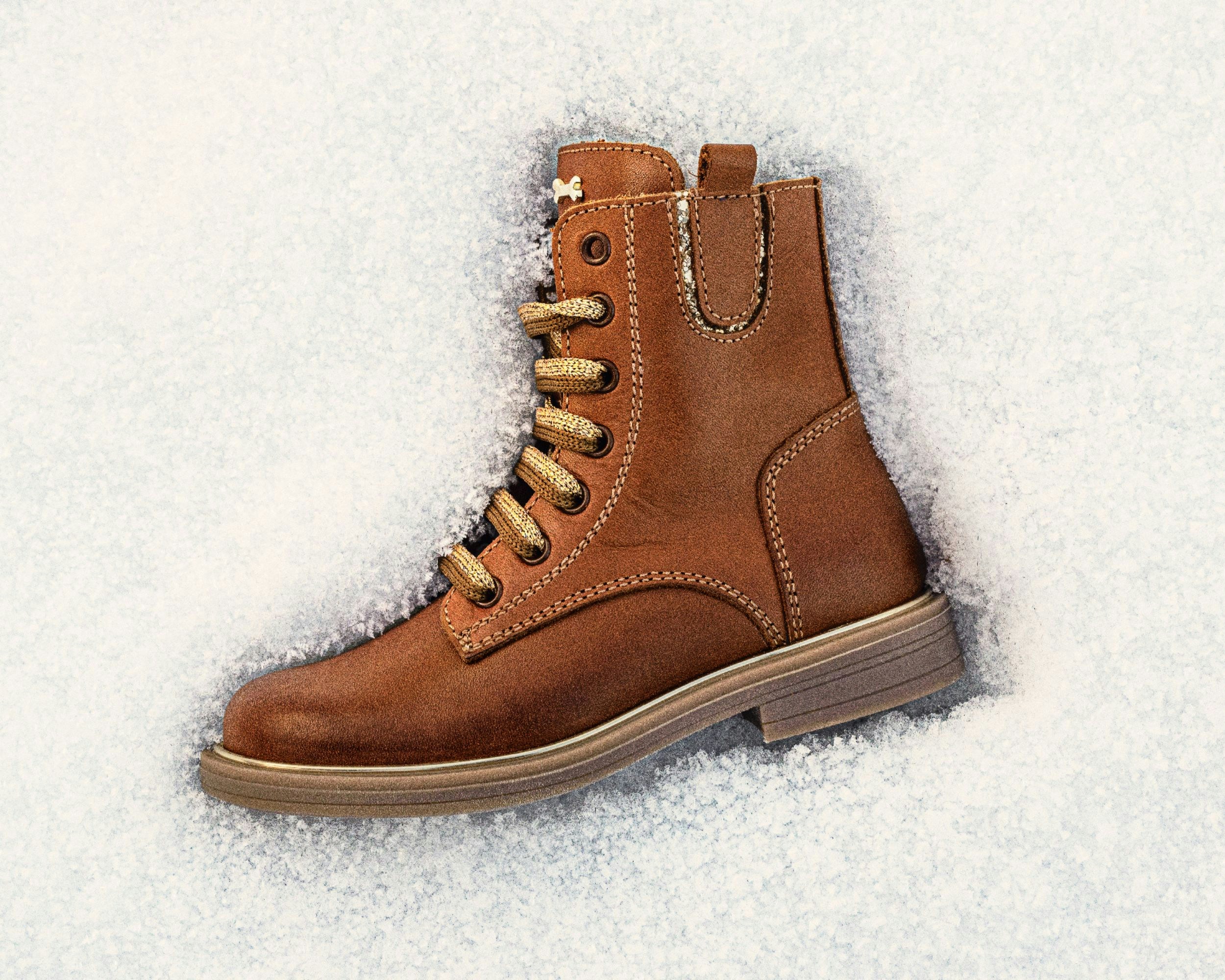 A brown boot rests on snow.