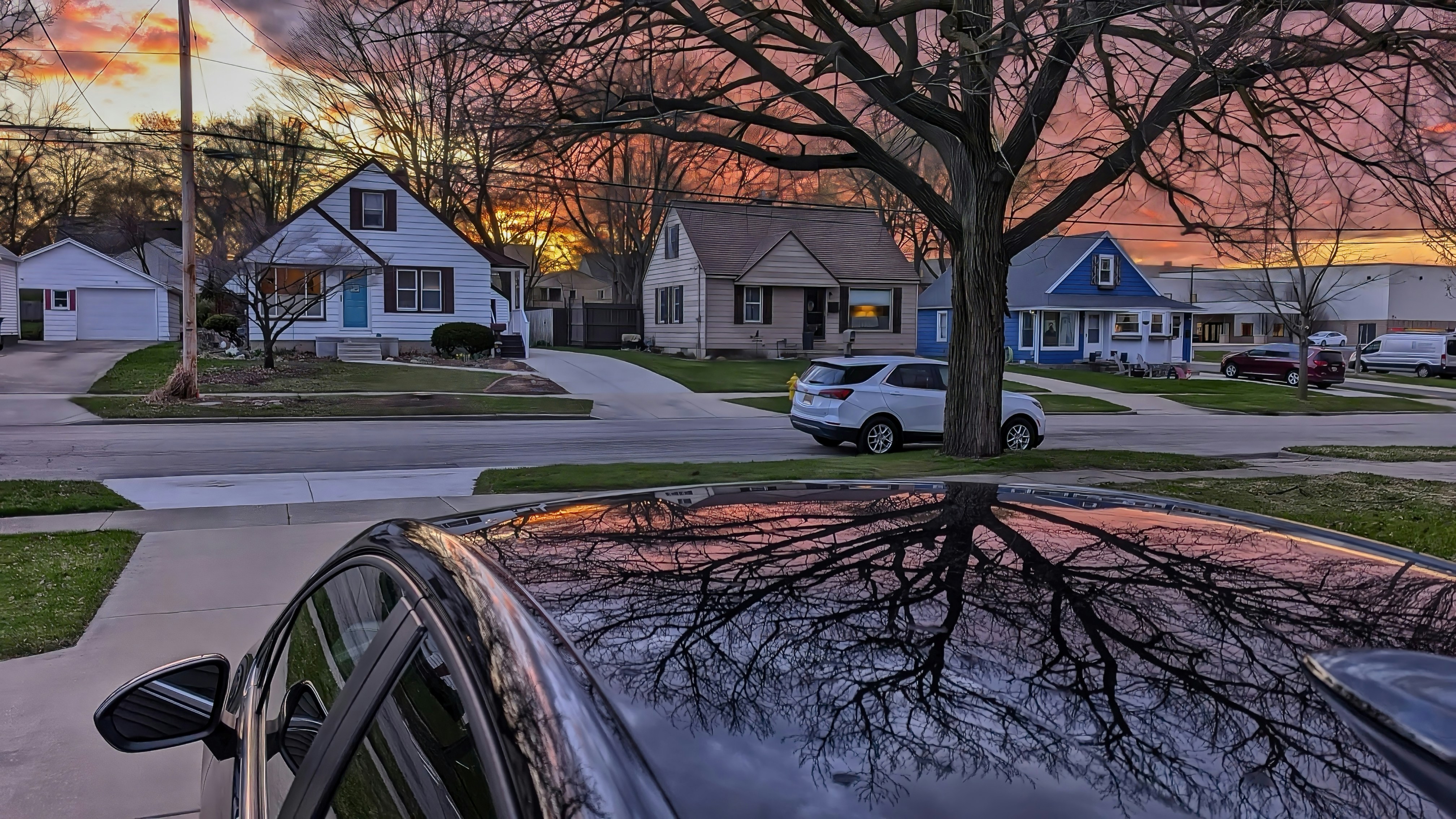 Sunset sky reflects off of a car's hood.
