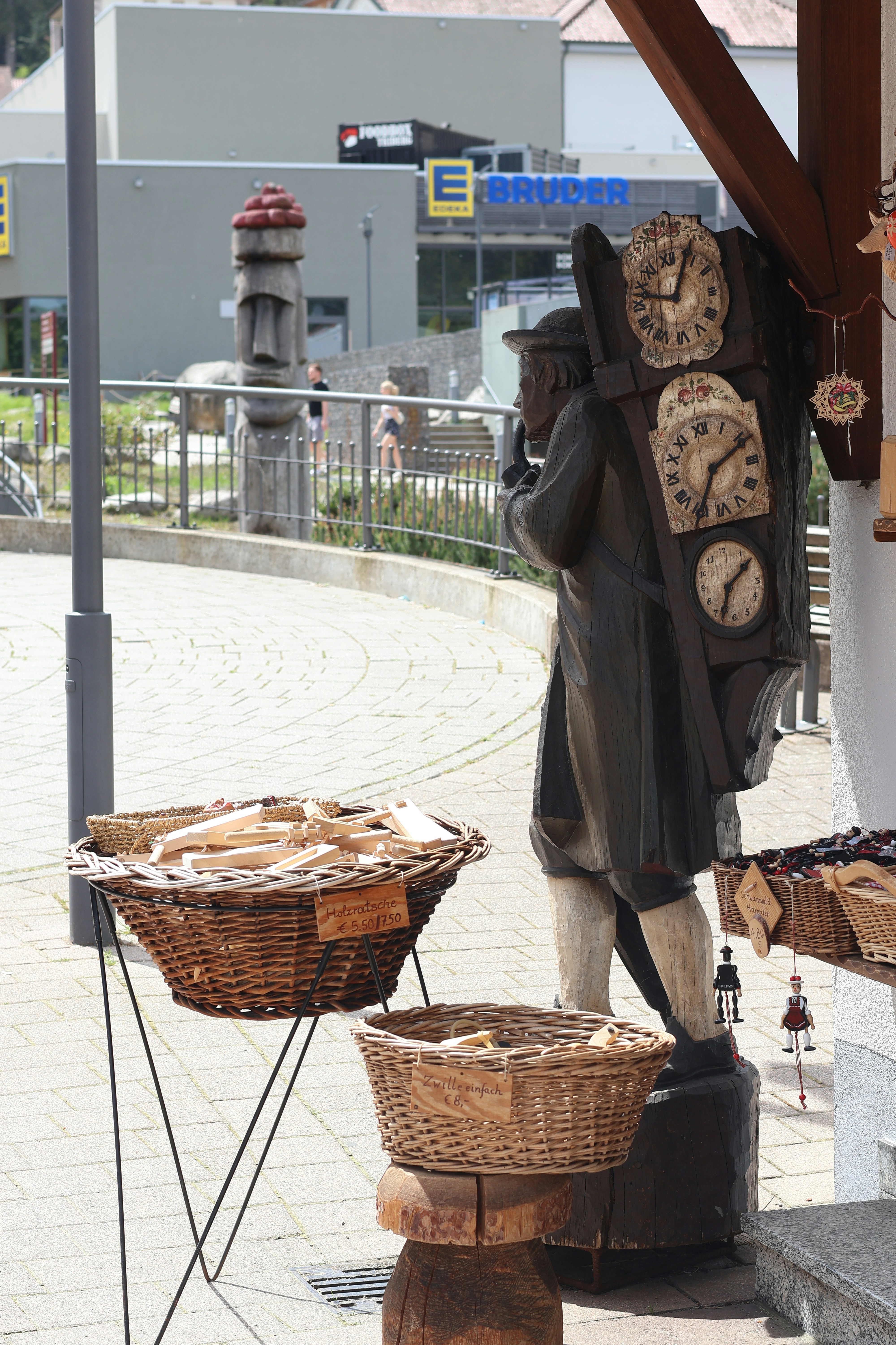A wooden sculpture stands near wicker baskets.