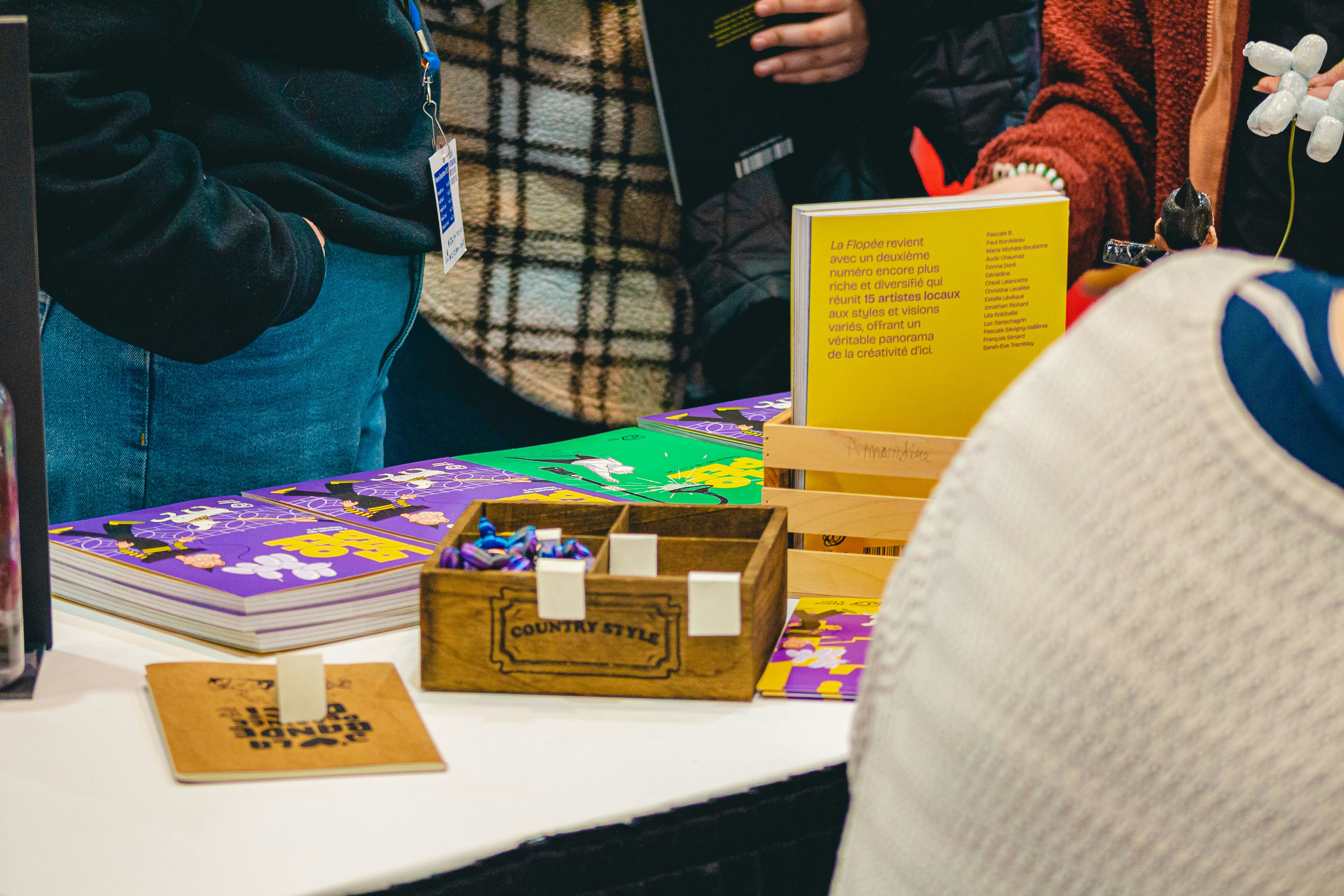 A craft fair table displays games and books.