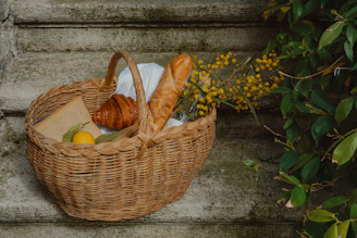 Picnic basket, bread, and pastries ready to enjoy.