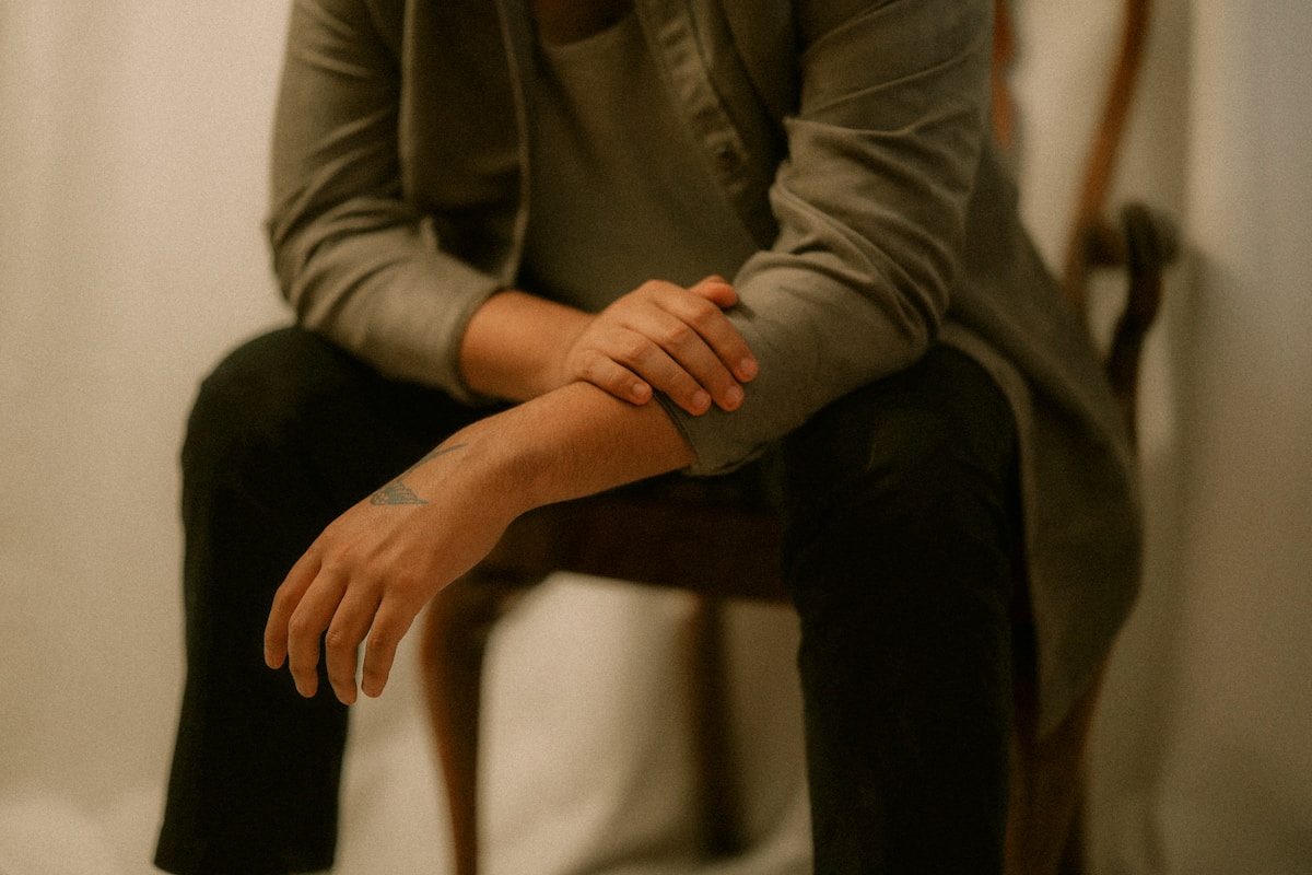 A person sits on a chair with arms crossed.