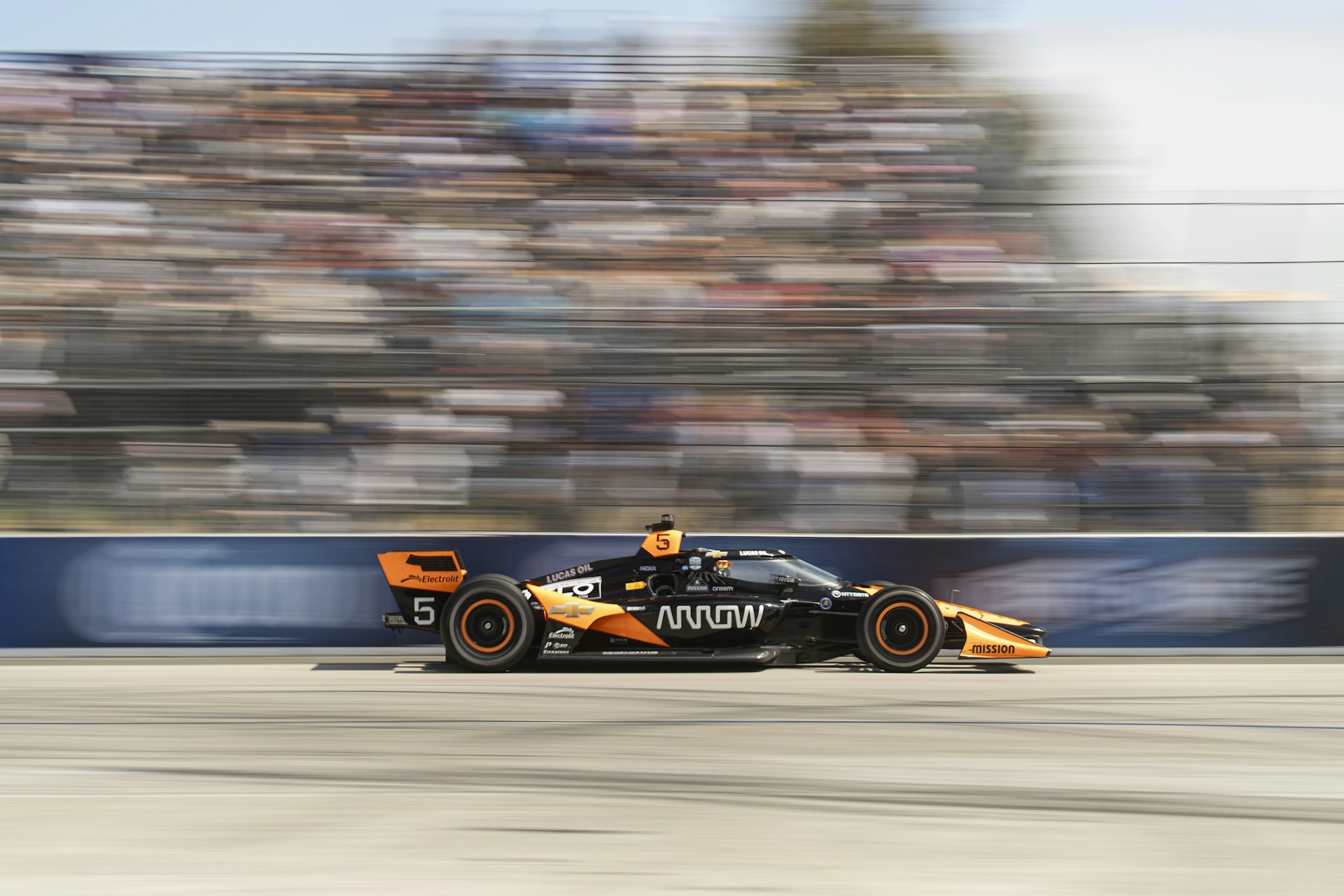 A race car speeds past the blurry crowd.