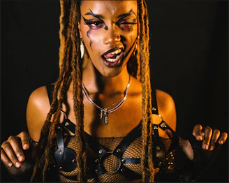 Woman with dreadlocks and artistic makeup poses.