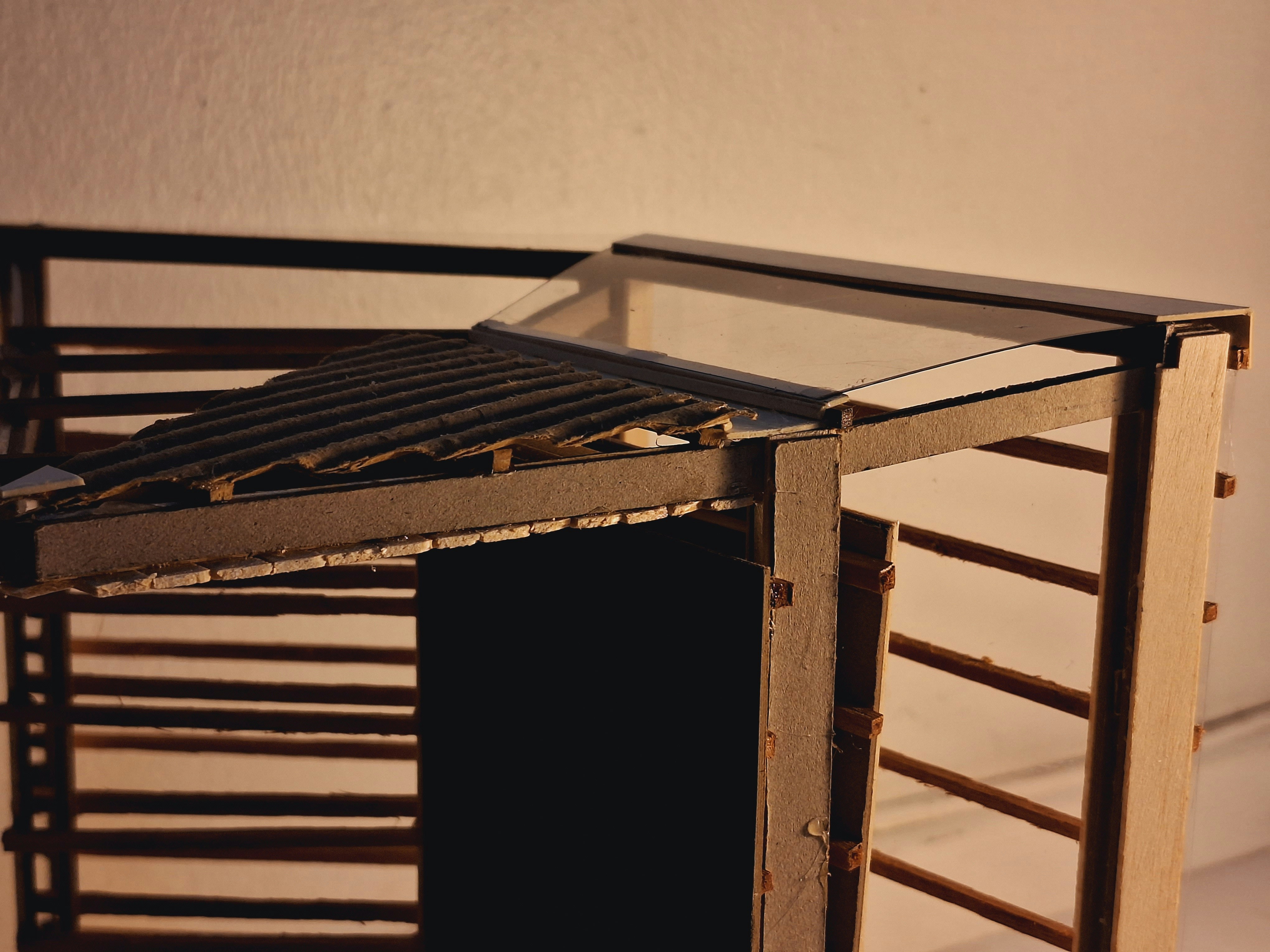 A miniature wooden structure with a glass roof.