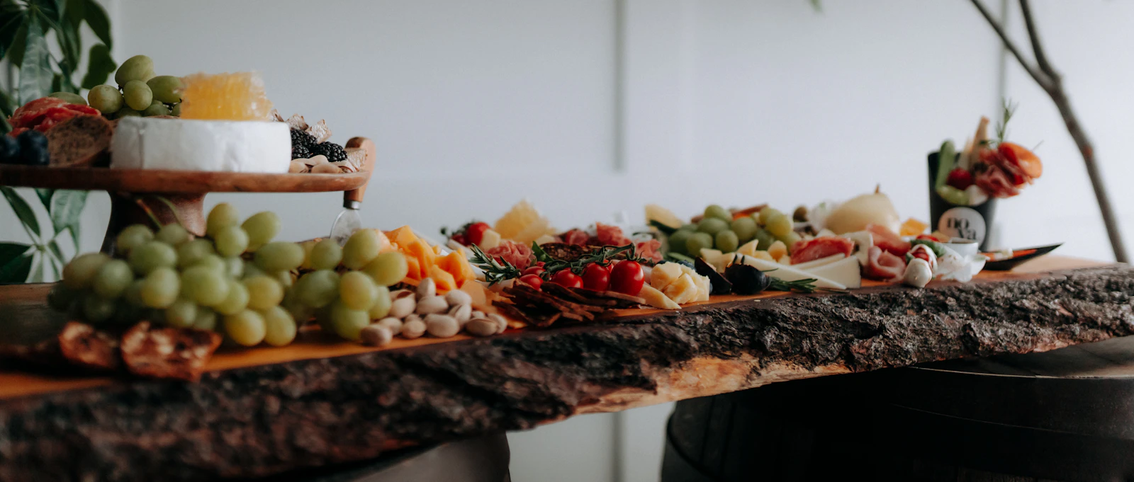 A long grazing table with fruit, cheese, and charcuterie on a natural wood slab