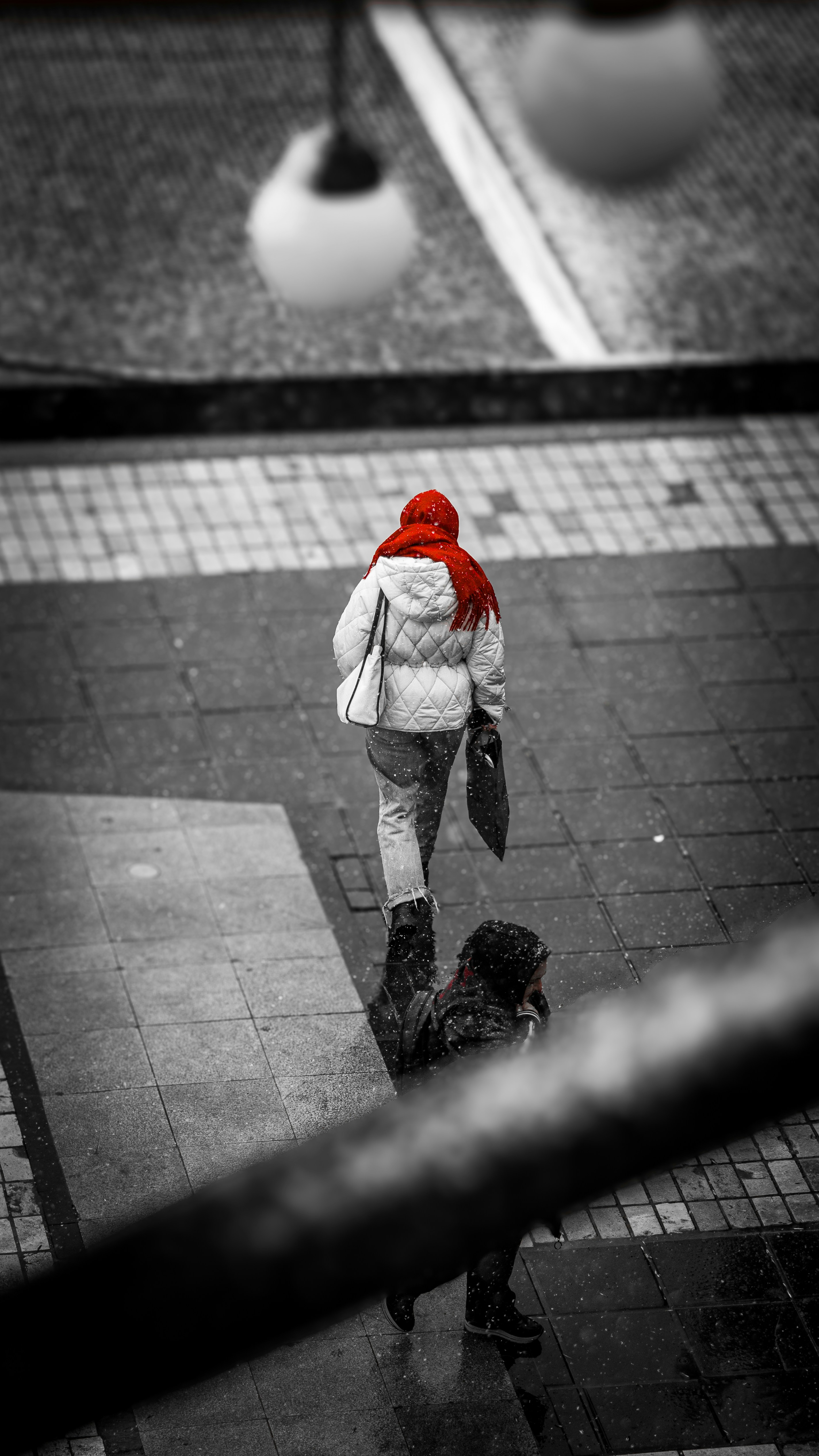 Woman with a red scarf walks in the rain