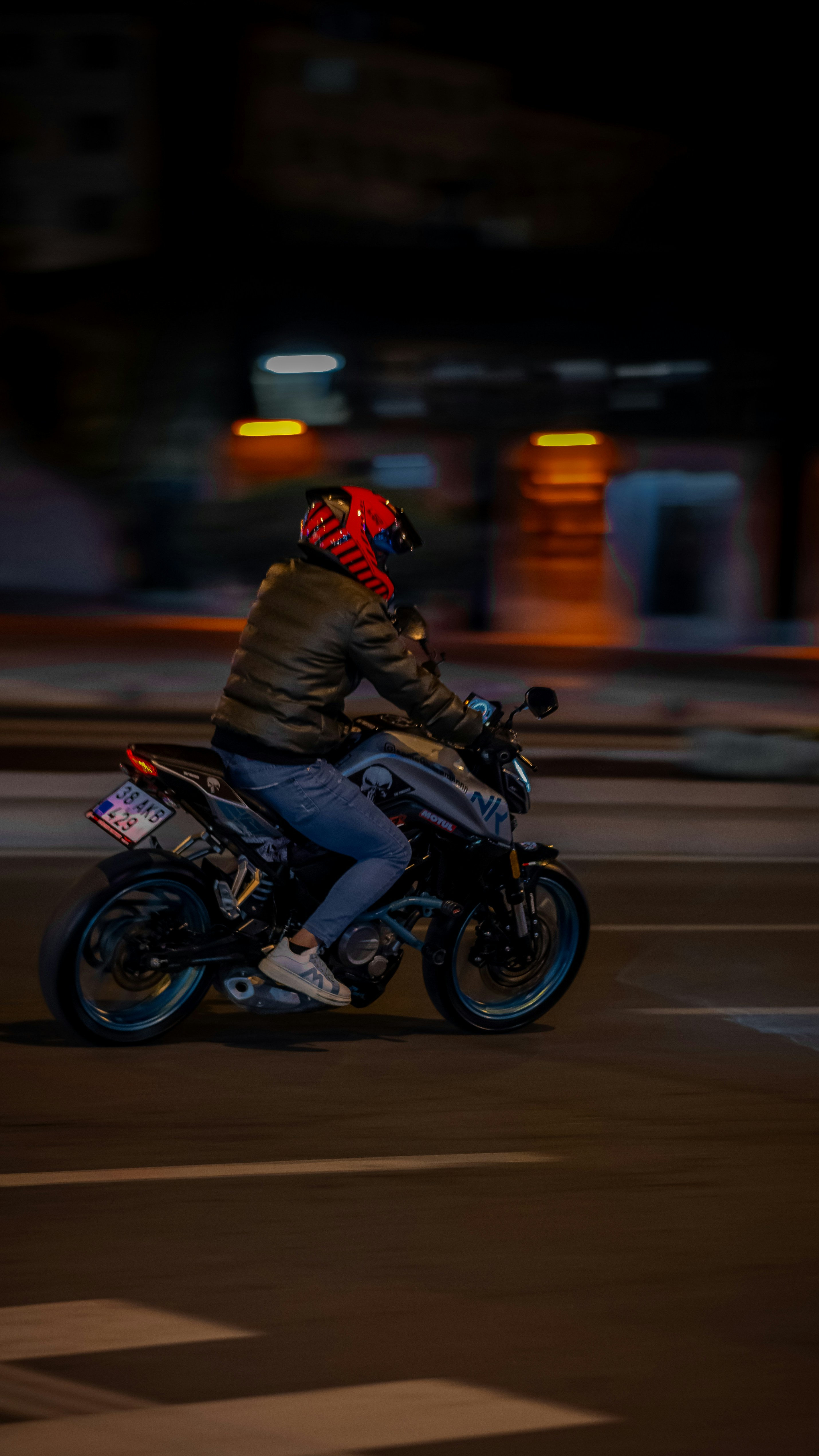 A motorcyclist rides down the street at night.