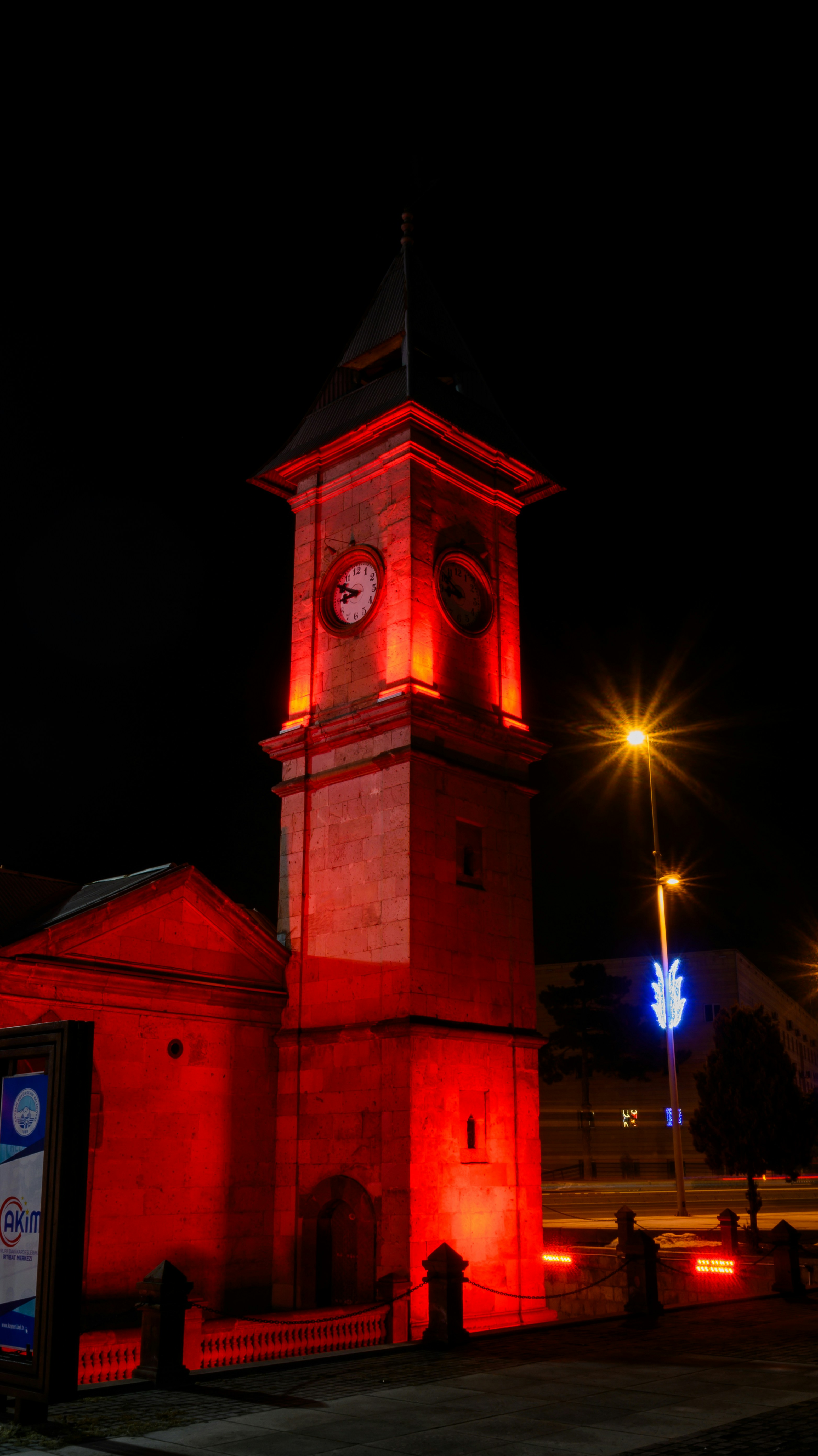 A red-lit clock tower stands at night.