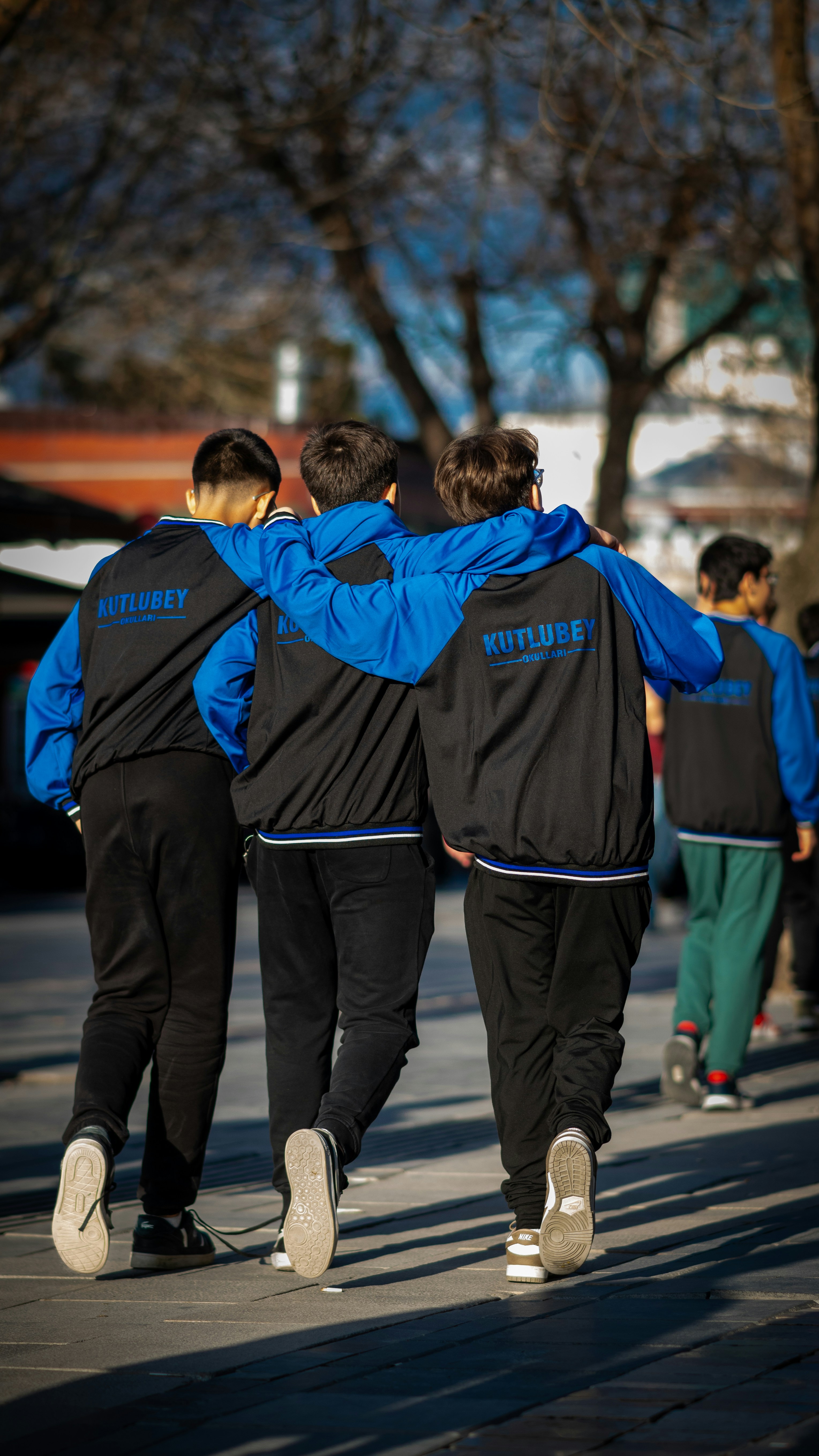 Three friends walk together, arms around each other.