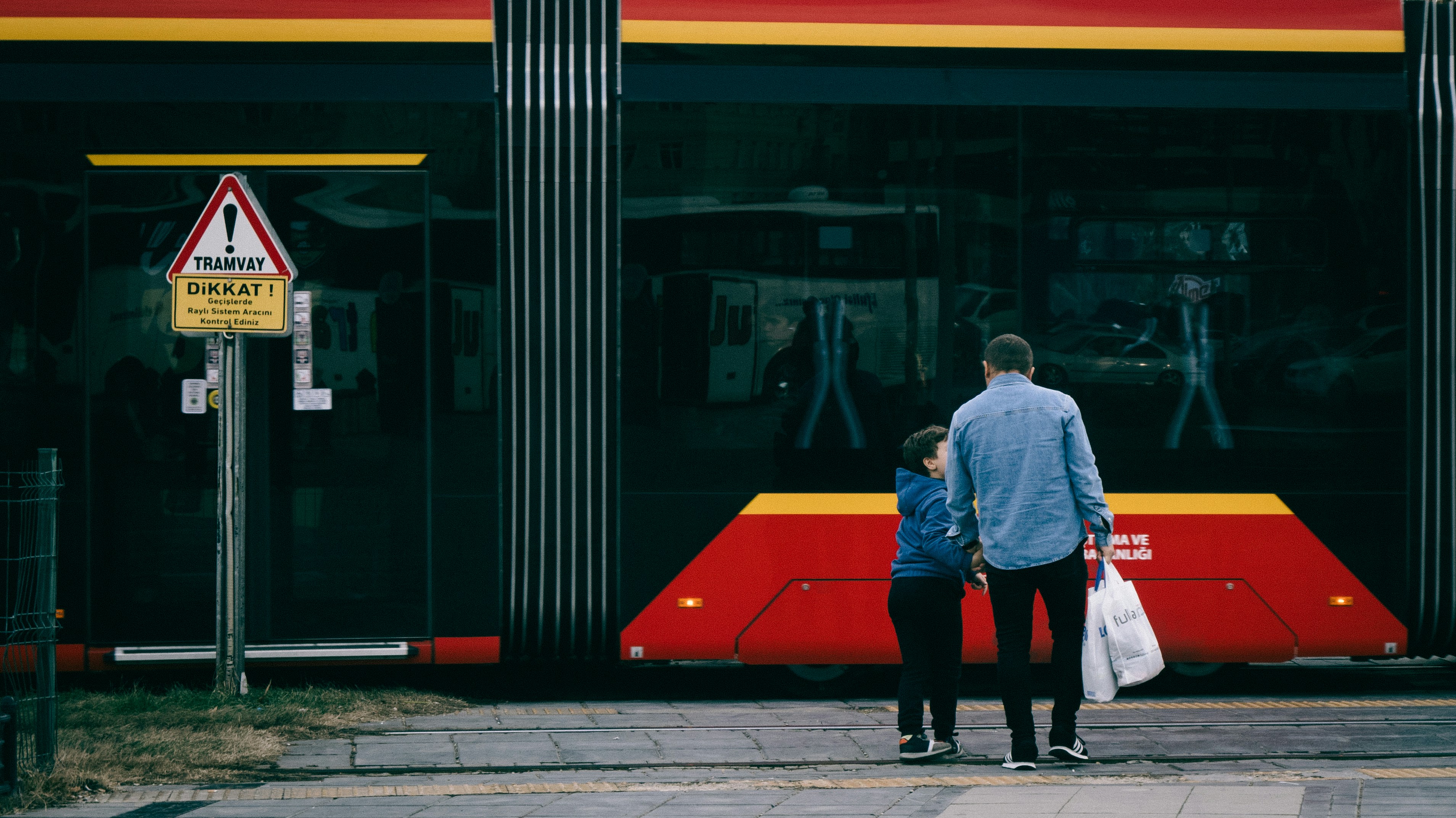 A father and child wait at a bus stop.