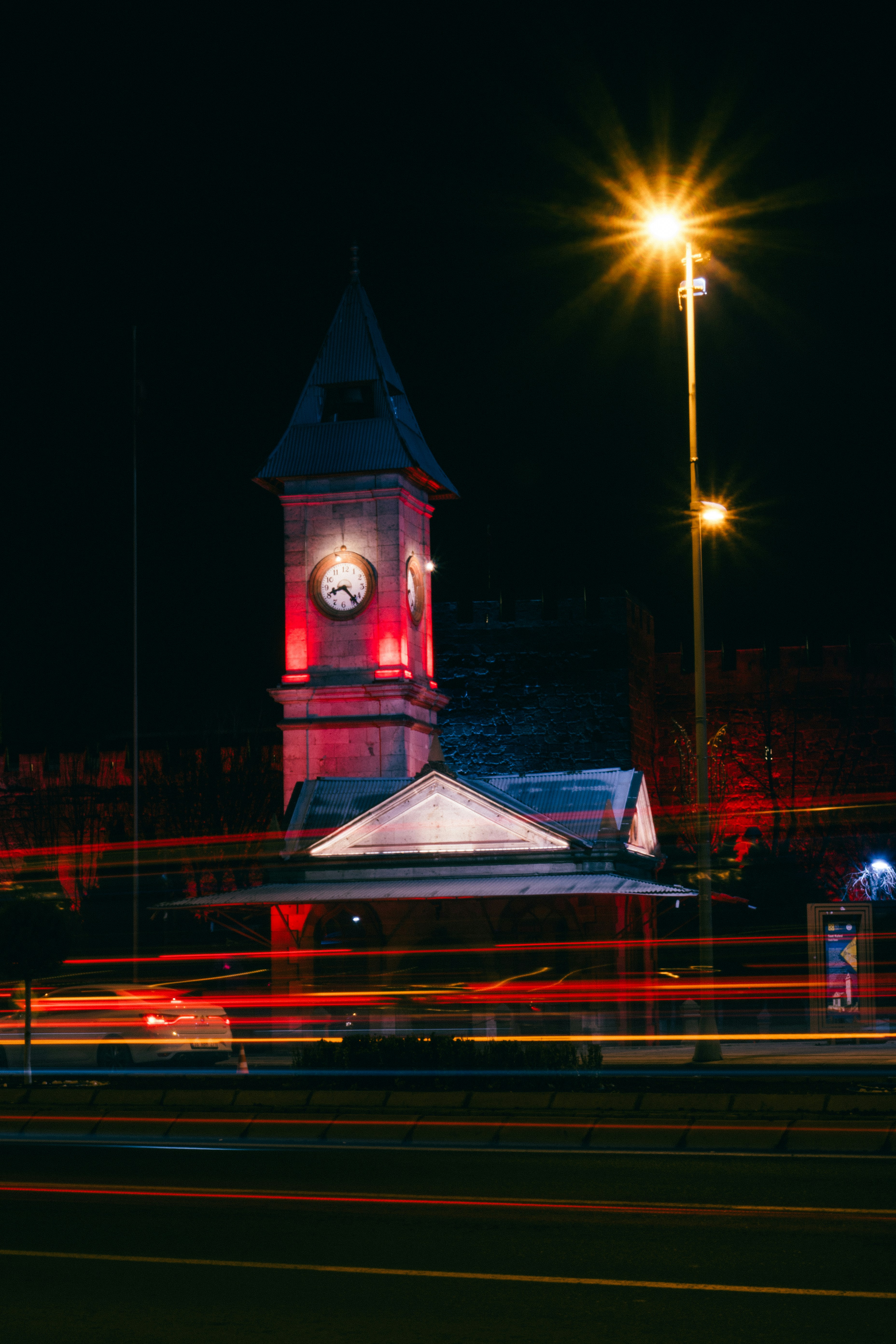 Clock tower illuminated at night with car trails.